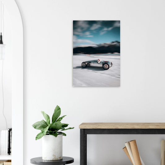 Room interior with a framed picture of a vintage car on the wall, a plant, and a desk.